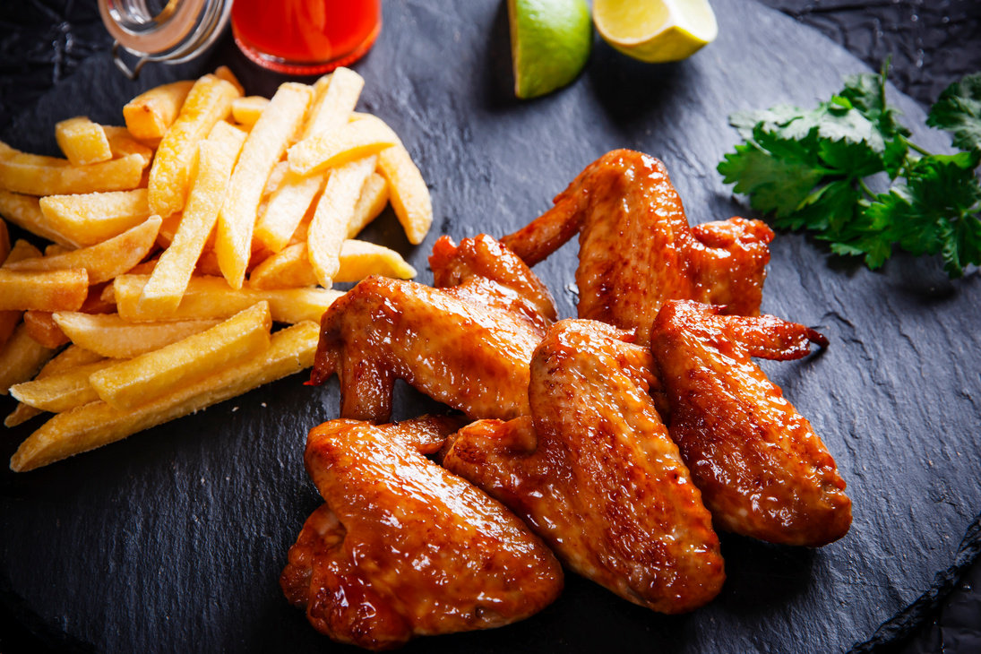 Fried chicken wings with potato on black stone